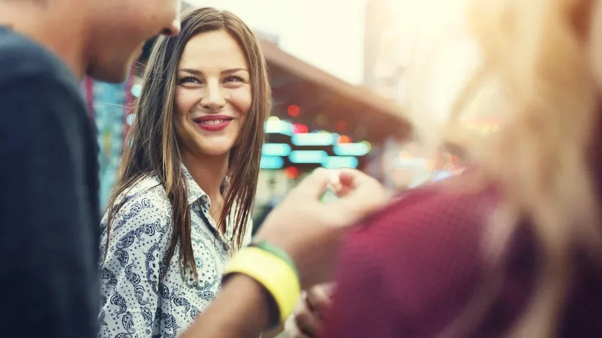 Woman smiling at another person who is wearing a bright yellow wristband. 