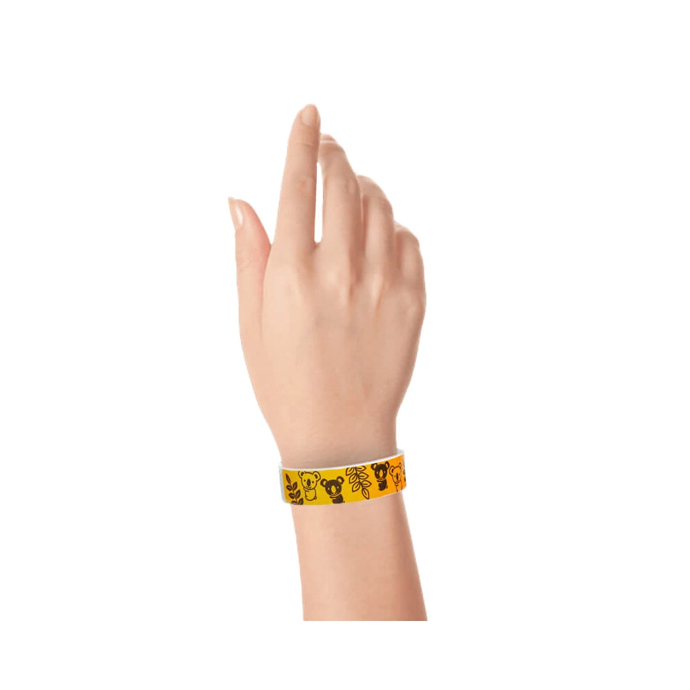 hand wearing a neon orange tyvek wristband with a koala and leaves pattern in black ink