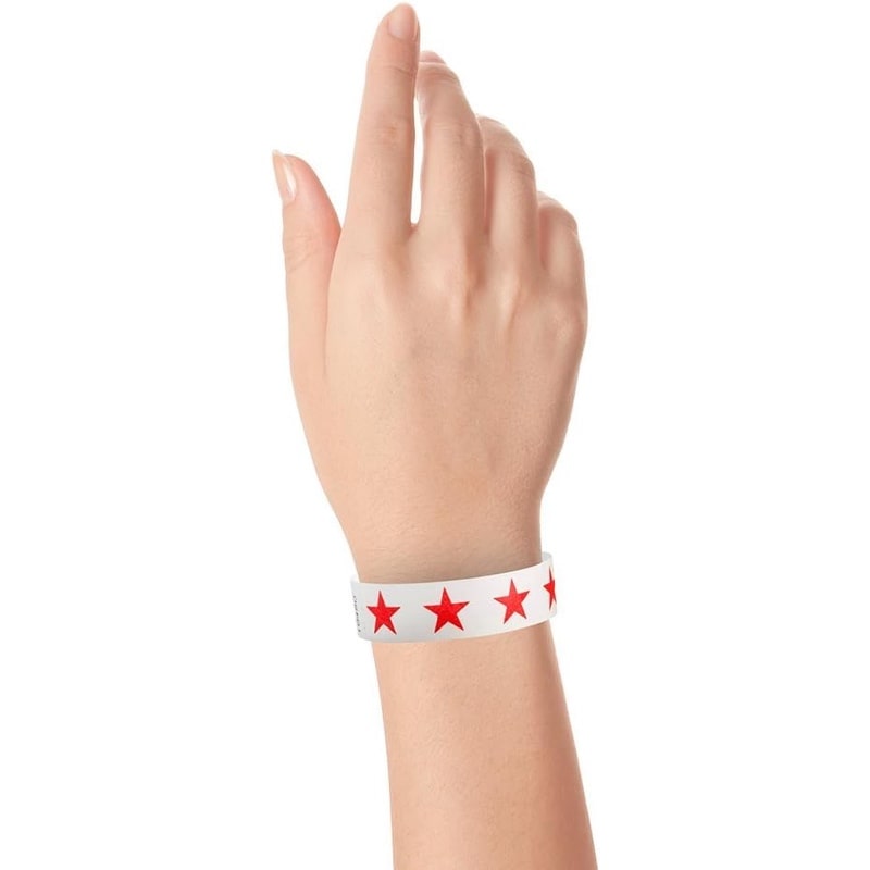 Hand wearing a white tyvek wristband with noen red stars 
